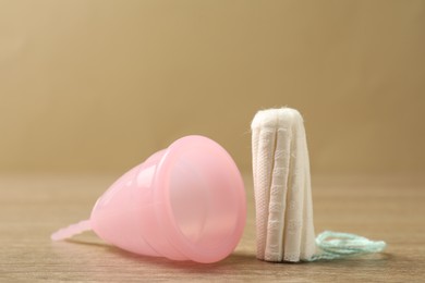 Photo of Menstrual cup and tampon on wooden table, closeup