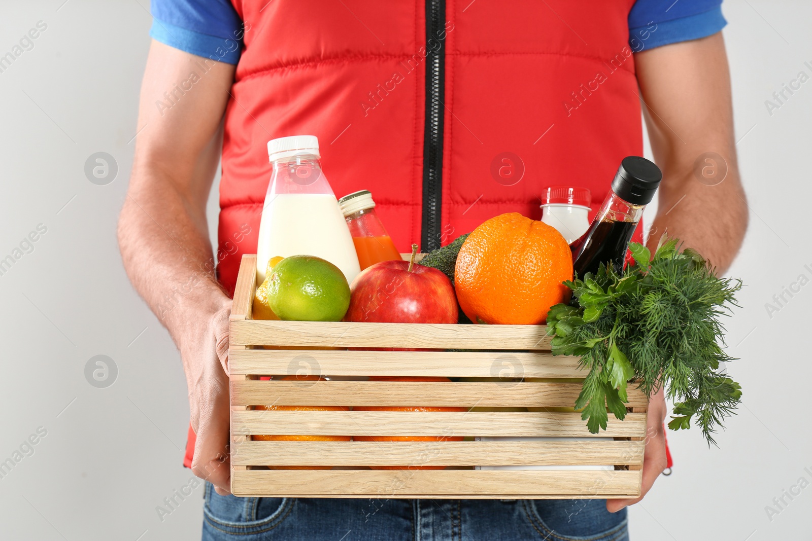 Photo of Courier with fresh products on light background, closeup. Food delivery service