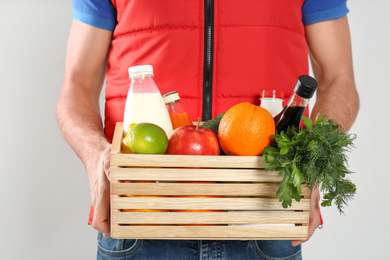 Courier with fresh products on light background, closeup. Food delivery service