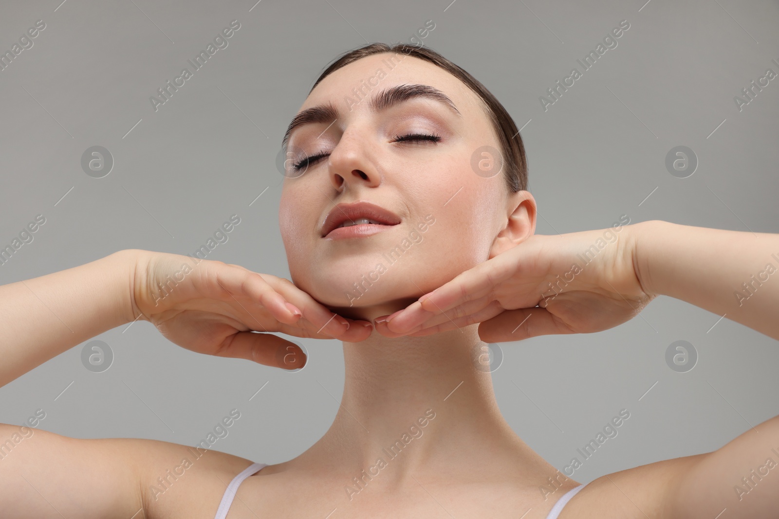 Photo of Beautiful woman touching her chin on grey background