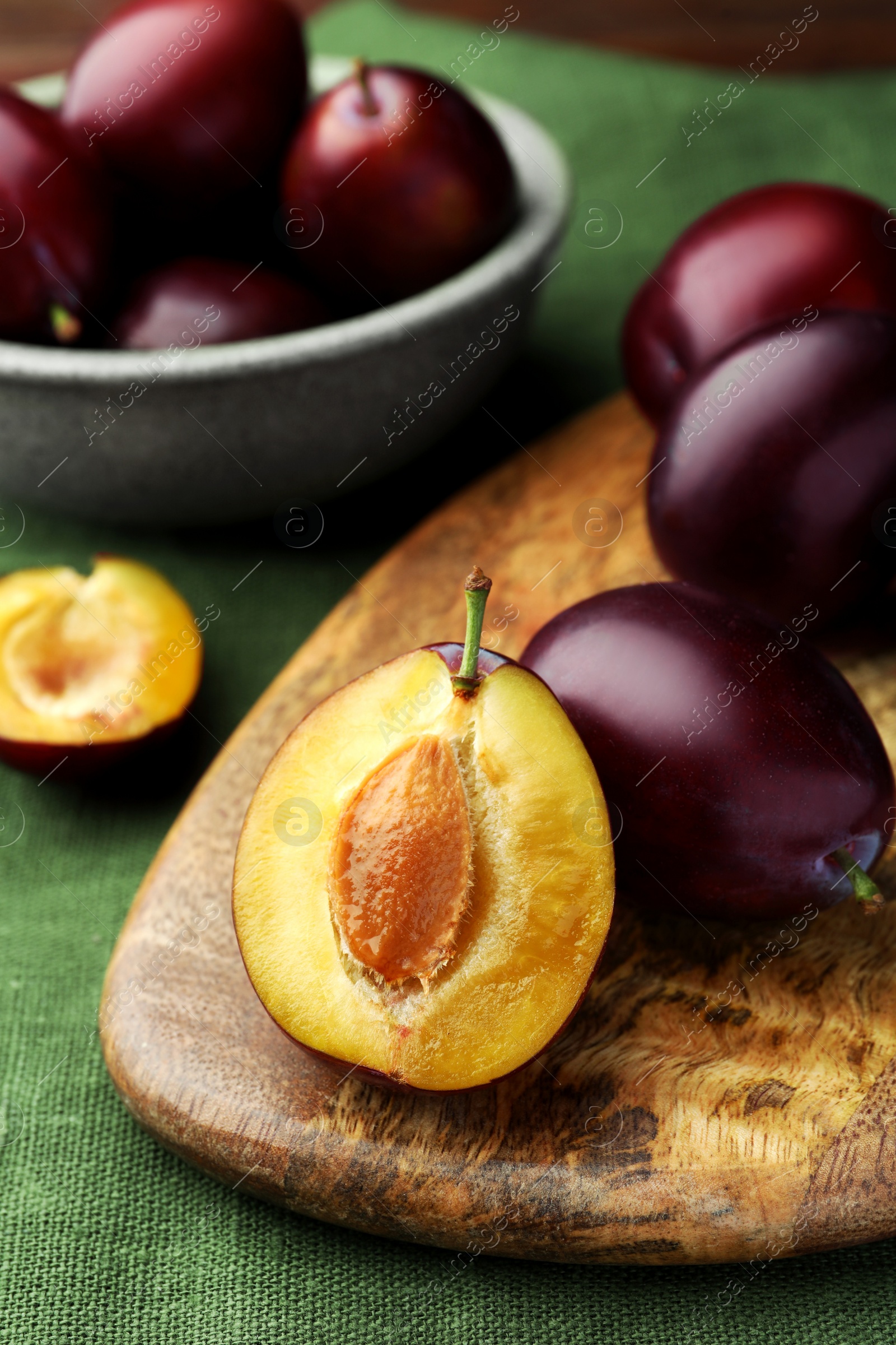 Photo of Many tasty ripe plums on green fabric