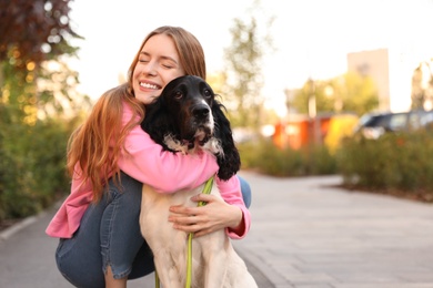 Photo of Young woman hugging her English Springer Spaniel dog outdoors. Space for text