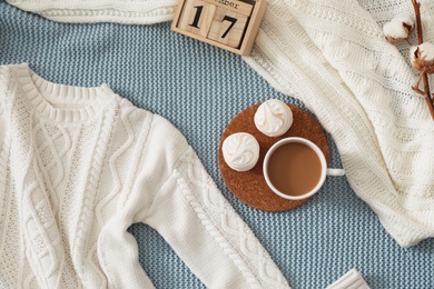 Flat lay composition with cozy knitted sweater on blanket