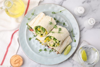 Delicious sandwich wraps with fresh vegetables, olive oil, sauce and slice of lime on white marble table, flat lay