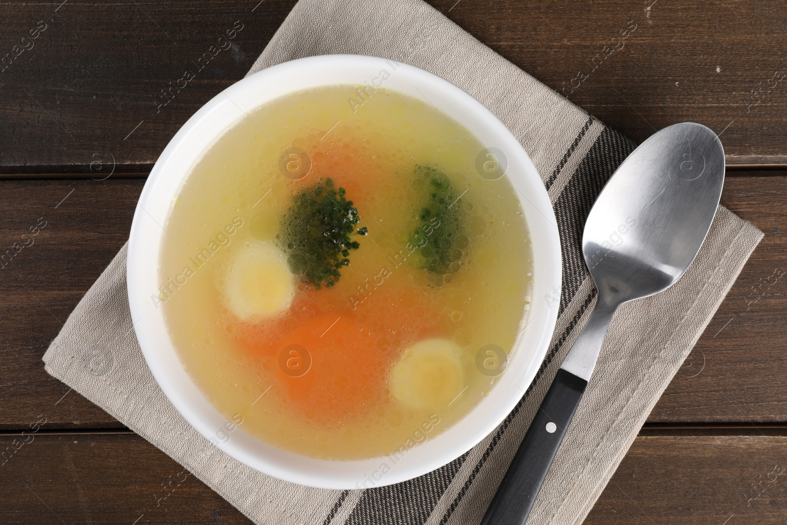 Photo of Tasty soup with vegetables in bowl served on wooden table, top view