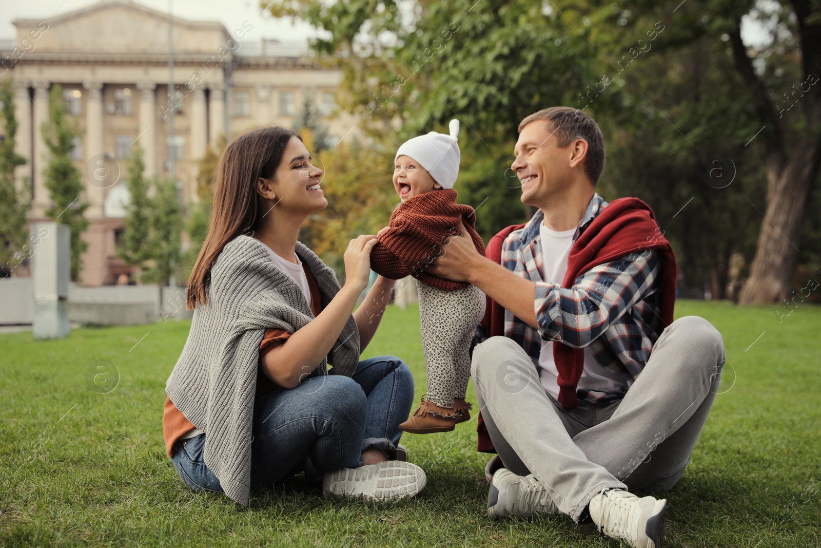 Photo of Happy parents with their adorable baby on green grass in park