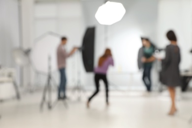 Photo of Blurred photo studio with professional equipment and team of workers