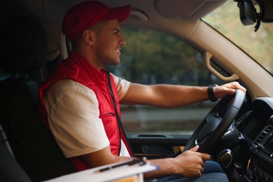 Courier in uniform on driver's seat of car