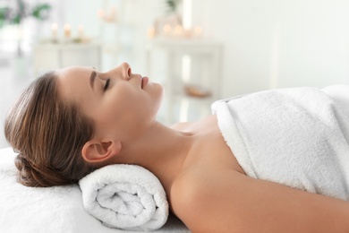 Photo of Young woman lying on massage table in spa salon