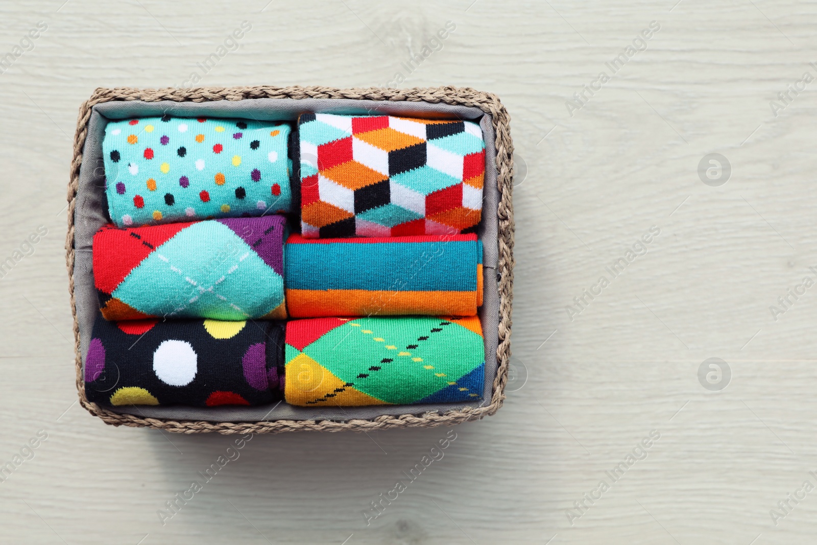 Photo of Box with colorful socks on wooden background, top view