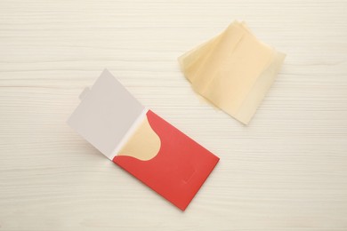 Photo of Package with facial oil blotting tissues on white wooden table, flat lay. Mattifying wipes