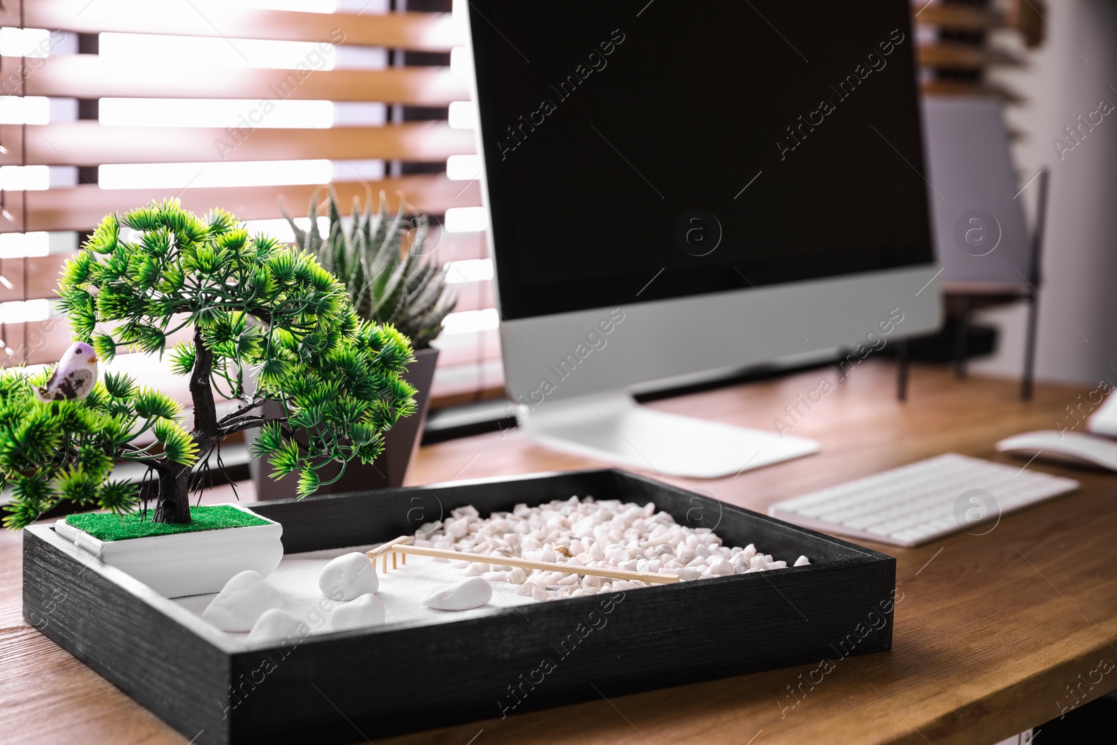 Photo of Modern workplace with beautiful miniature zen garden and computer in room