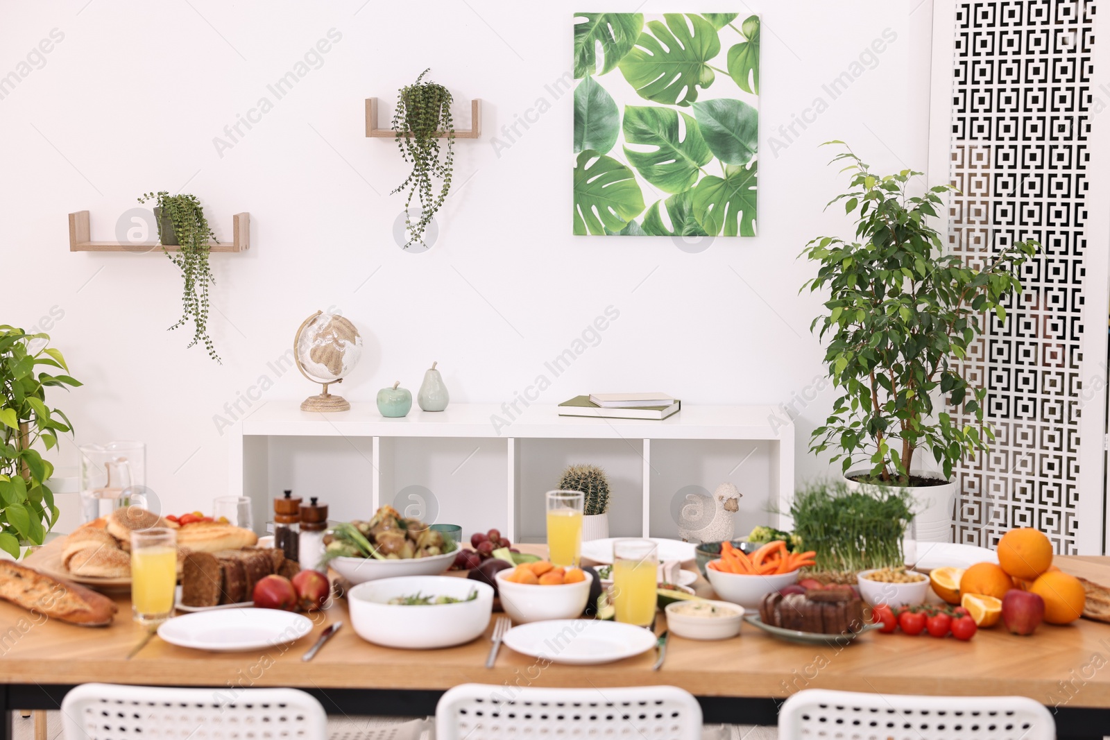 Photo of Healthy vegetarian food, glasses of juice, cutlery and plates on wooden table indoors