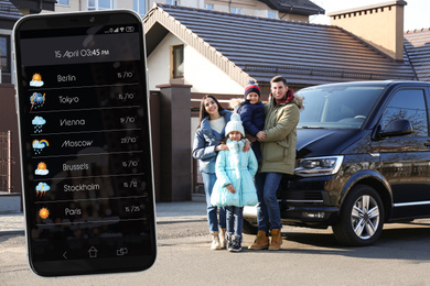 Happy family near modern car outdoors and smartphone with open weather forecast app 