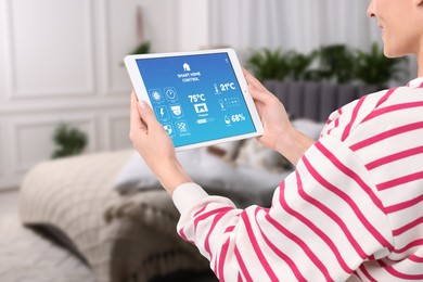 Woman using smart home control system via application on tablet indoors, closeup