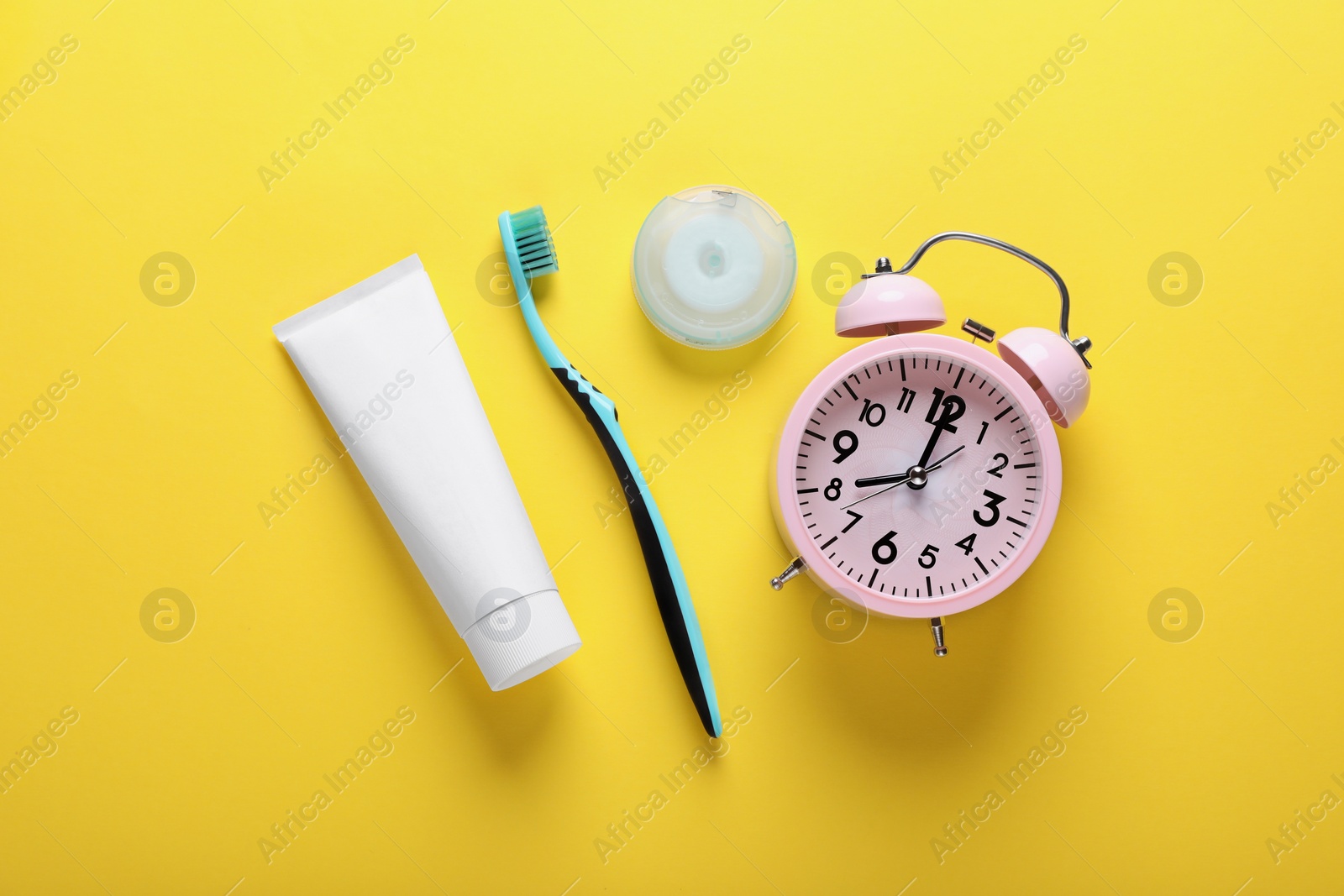 Photo of Container with dental floss, toothpaste and toothbrush on yellow background, flat lay