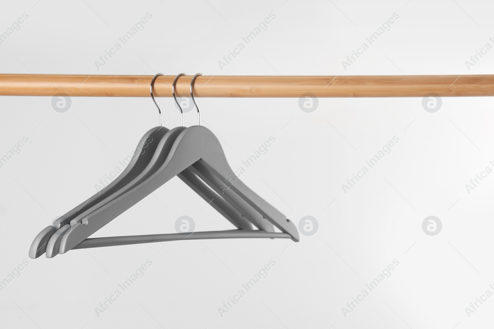 Photo of Wooden rack with clothes hangers on white background, space for text