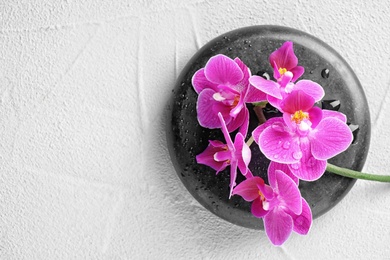 Orchid with spa stone on light grey background, top view. Space for text