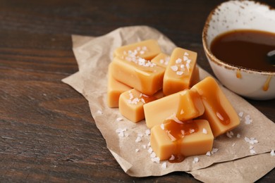 Photo of Delicious candies with sea salt and caramel sauce on wooden table, closeup. Space for text