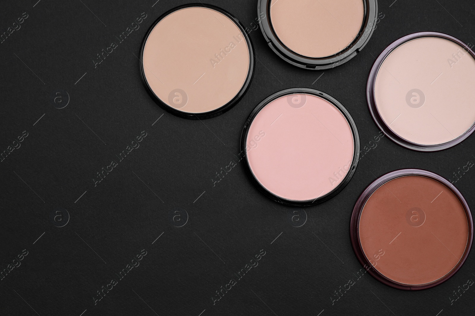 Photo of Different face powders on black background, flat lay. Space for text