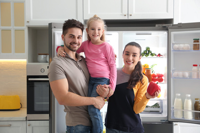 Photo of Happy family near open refrigerator in kitchen