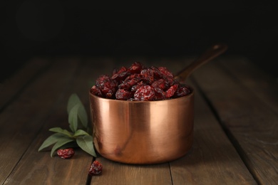 Photo of Copper pot with dried cranberries on wooden table