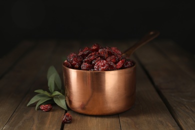 Copper pot with dried cranberries on wooden table