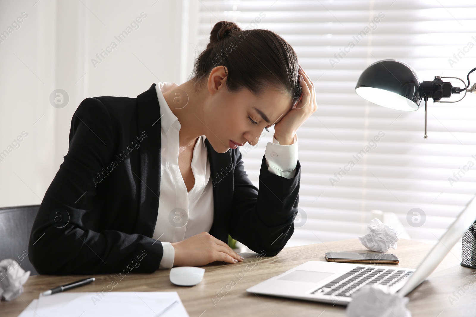 Photo of Stressed and tired young woman at workplace