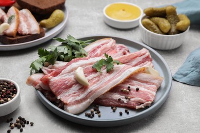 Slices of tasty pork fatback with spices on grey table, closeup