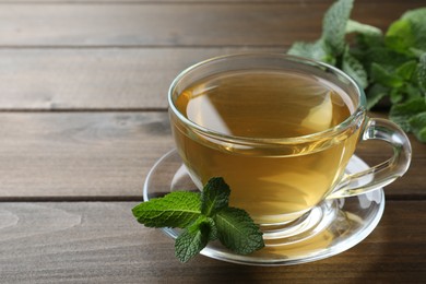 Cup of aromatic green tea with fresh mint on wooden table. Space for text