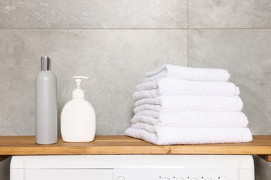 Stack of clean towels and cosmetic products in laundry room