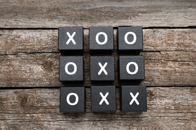 Photo of Tic tac toe cube set on wooden table, flat lay