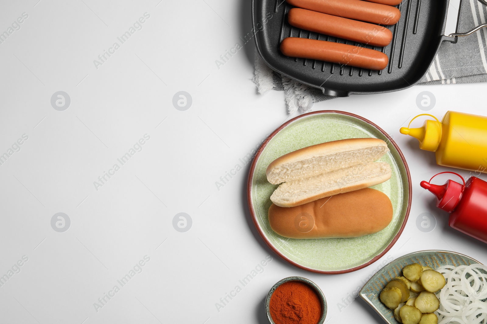 Photo of Different tasty ingredients for hot dog on white table, flat lay. Space for text