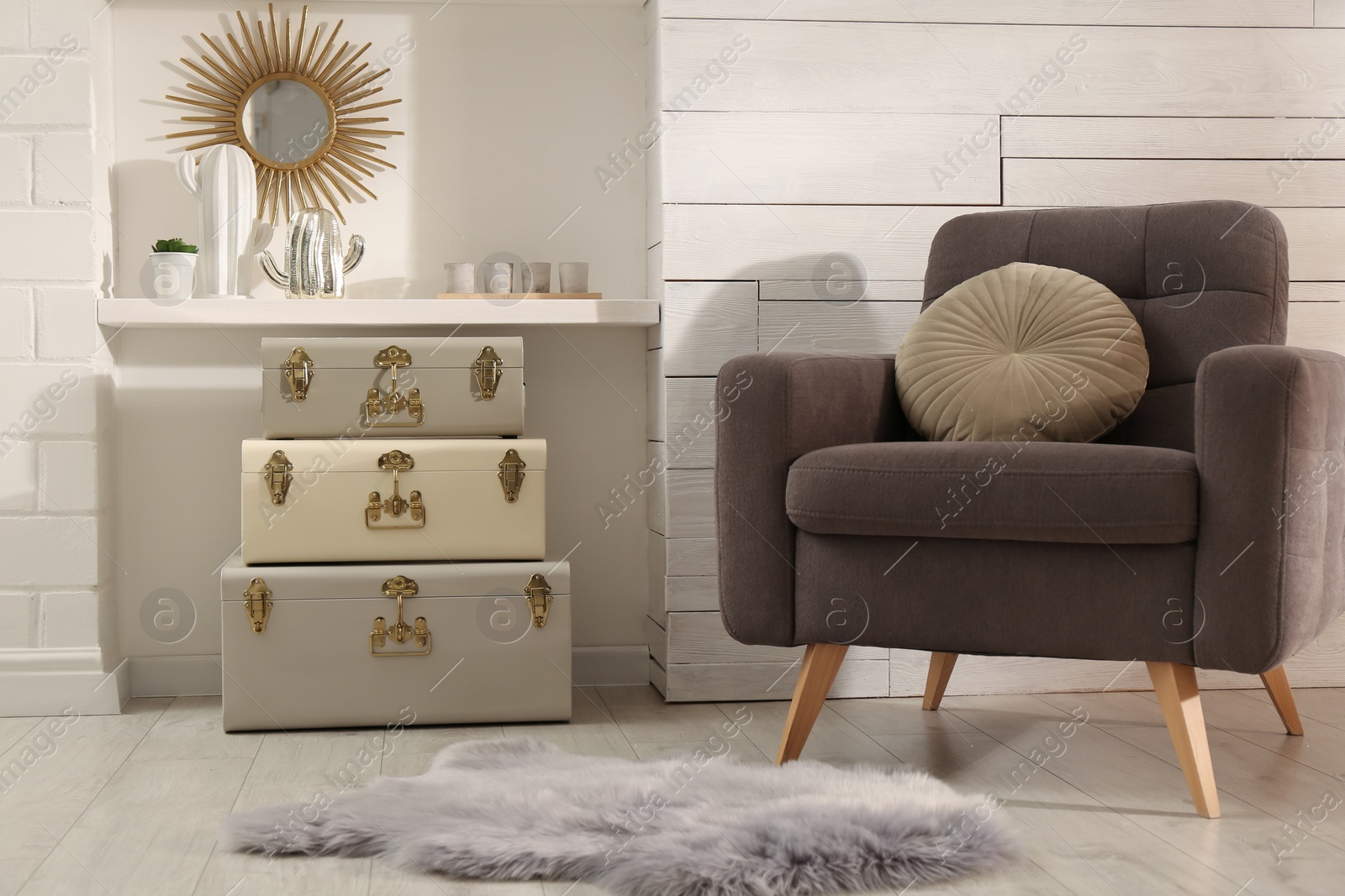 Photo of Stylish room interior with comfortable armchair and storage trunks near white wall