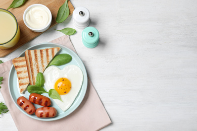 Tasty breakfast with heart shaped fried egg served on white wooden table, flat lay. Space for text