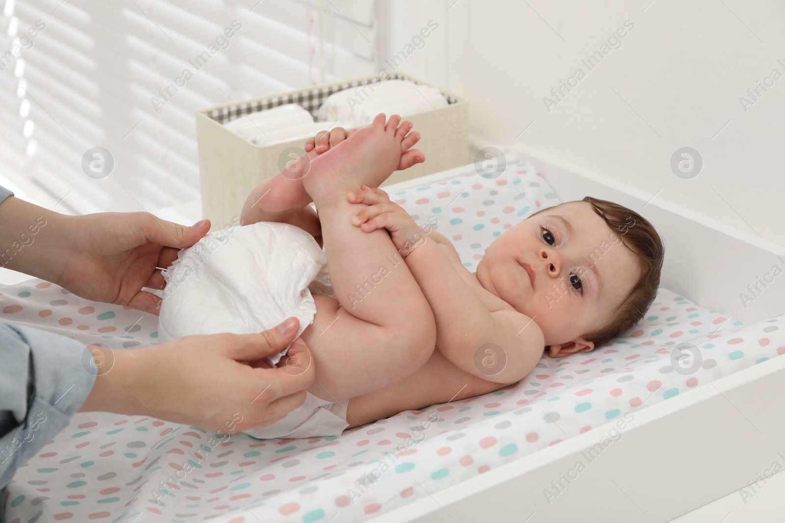 Photo of Mother changing baby's diaper on table at home, closeup