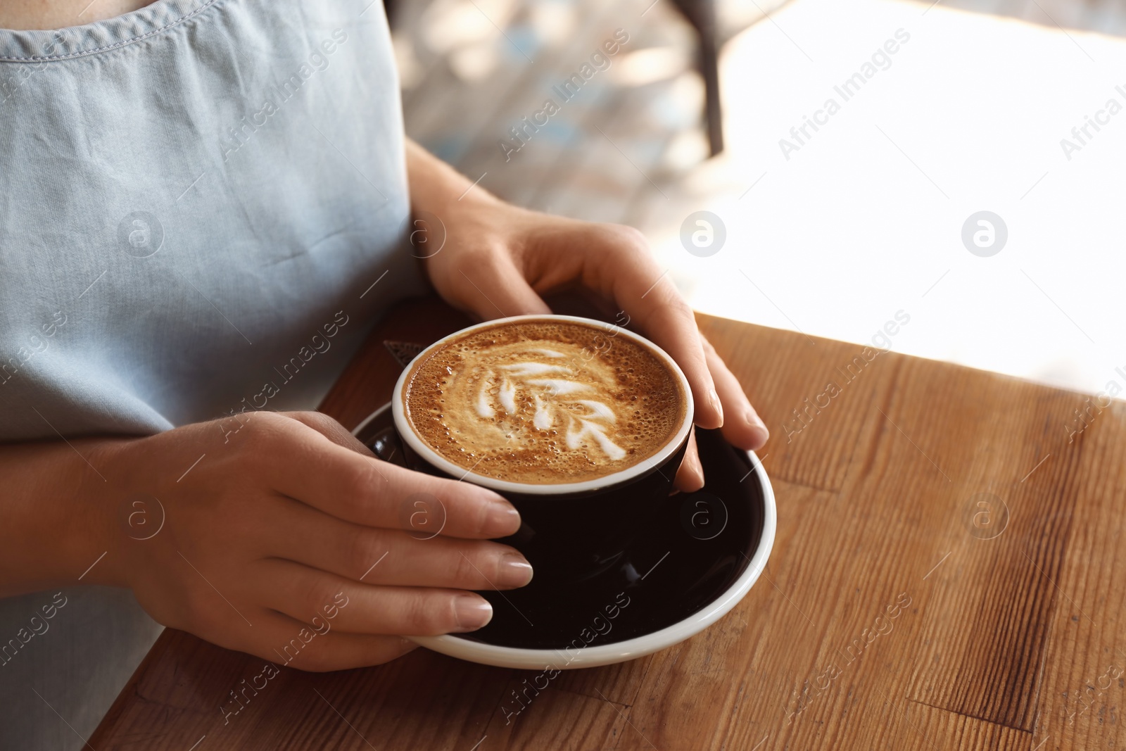 Photo of Woman with cup of fresh aromatic coffee at table, closeup