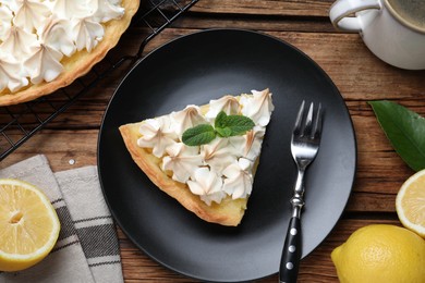 Photo of Piece of delicious lemon meringue pie served on wooden table, flat lay