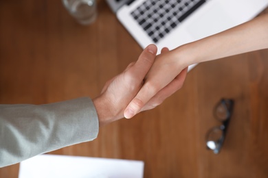 Business partners shaking hands over table after meeting, top view