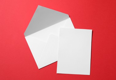 Letter envelope and card on red background, top view