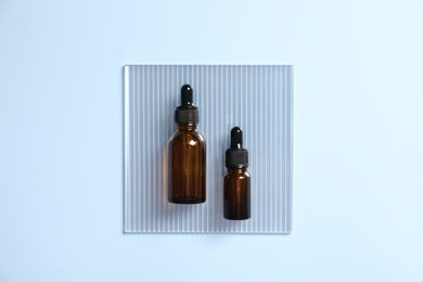 Photo of Bottles of cosmetic serum on light blue background, top view