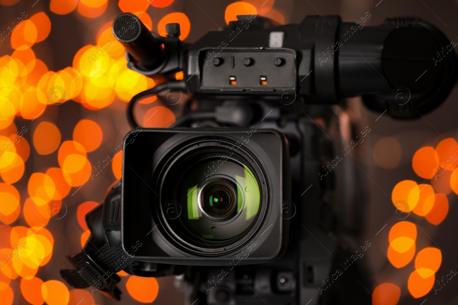 Photo of Modern video camera against blurred lights, closeup