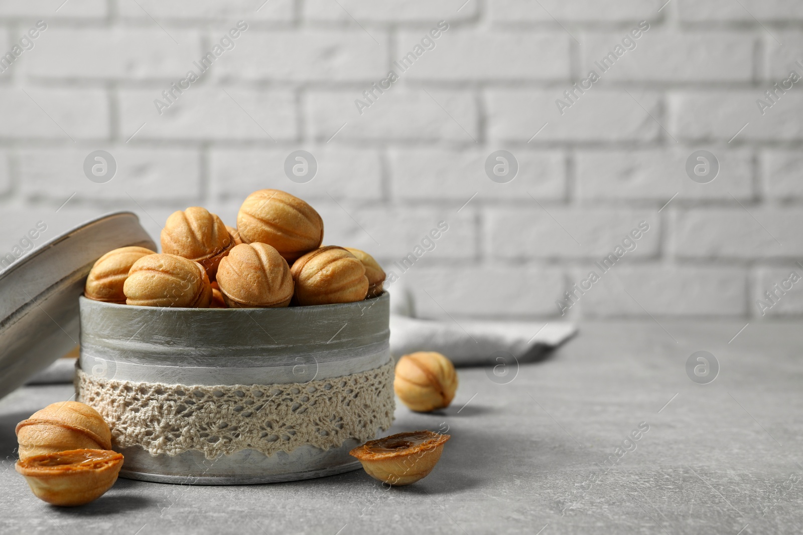 Photo of Delicious nut shaped cookies with boiled condensed milk on light grey table. Space for text