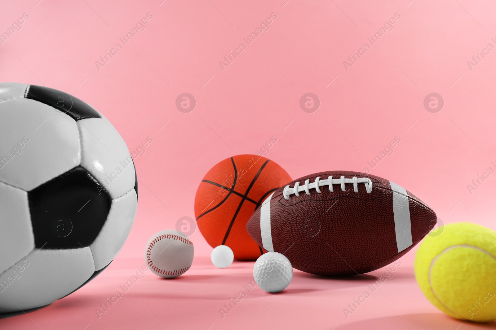 Photo of Many different sports balls on pink background, space for text