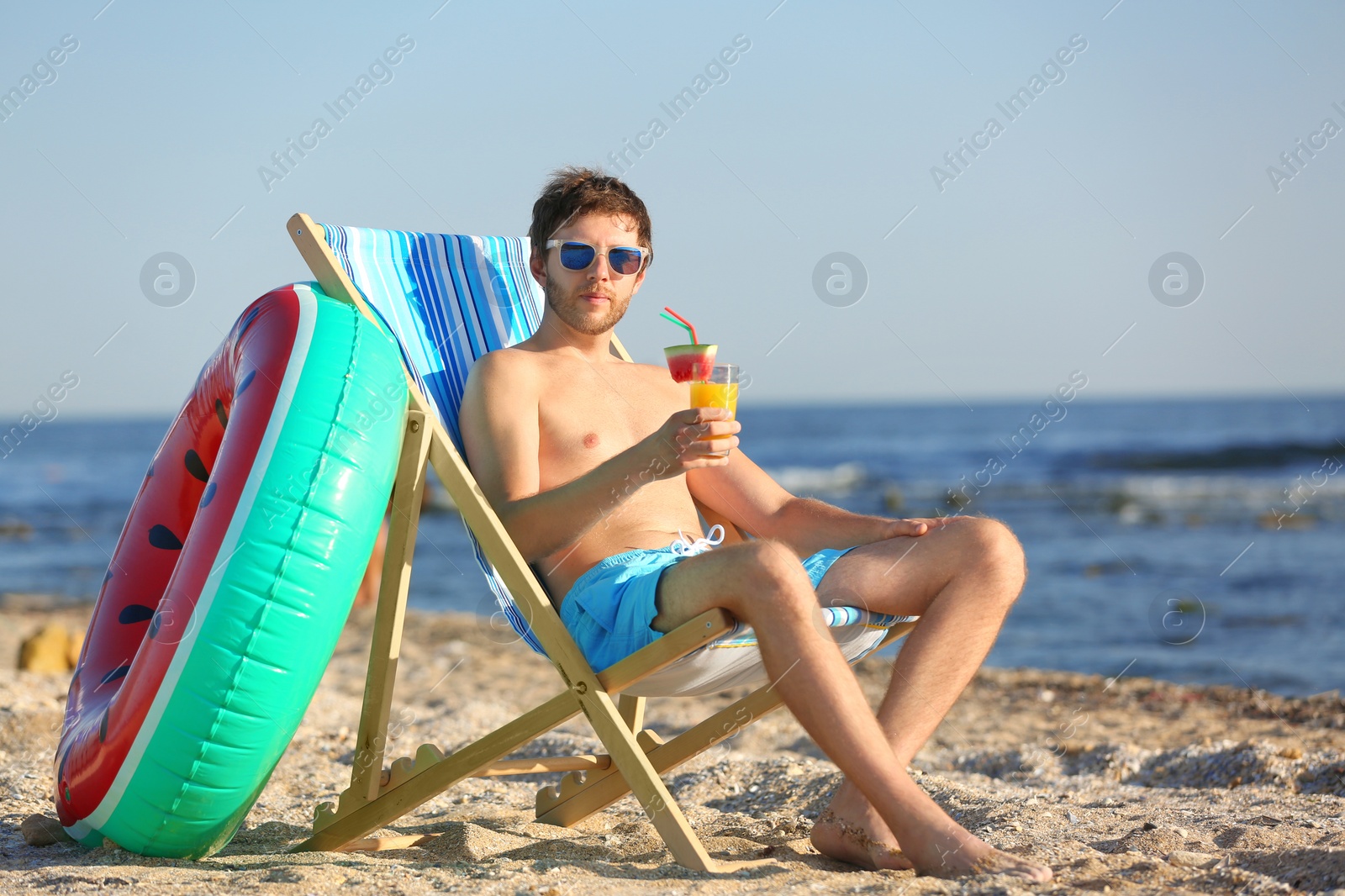 Photo of Young man with cocktail in beach chair at seacoast