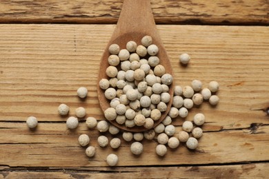 Aromatic spice. White pepper in spoon on wooden table, top view