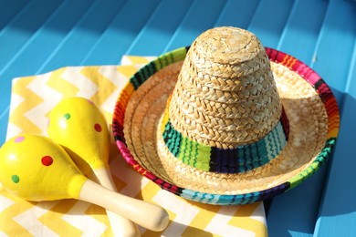 Mexican sombrero hat, towel and maracas on blue wooden surface