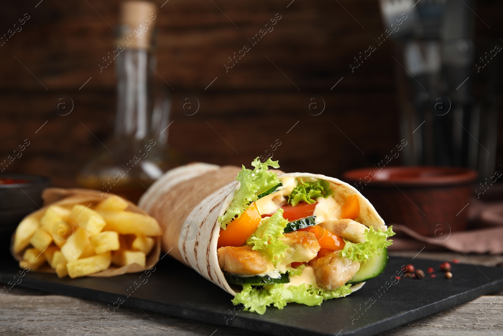 Photo of Delicious chicken shawarma and French fries on wooden table, closeup