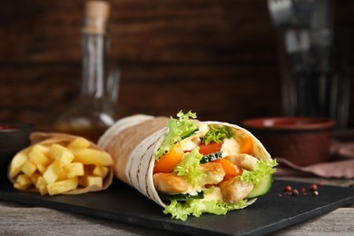 Delicious chicken shawarma and French fries on wooden table, closeup