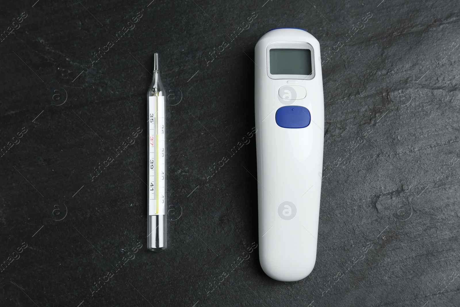 Photo of Non-contact infrared and mercury thermometers on black slate background, flat lay